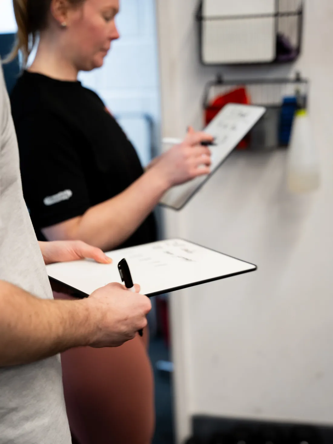 A coach writing a member's plan on a whiteboard clipboard