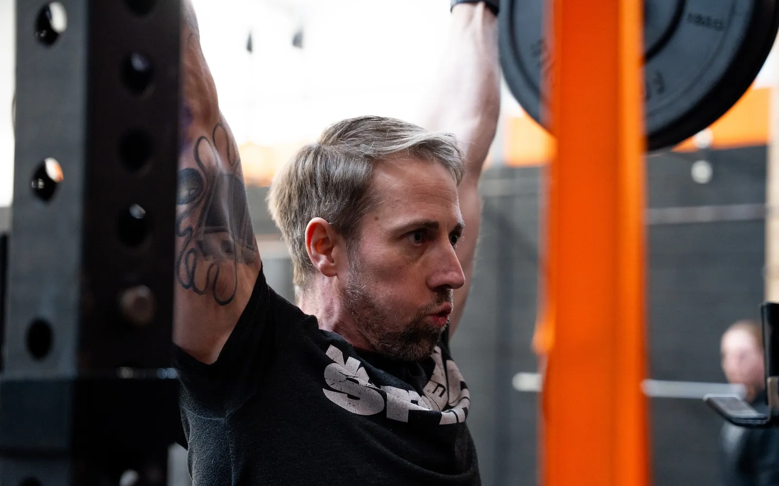 A member pressing a barbell overhead
